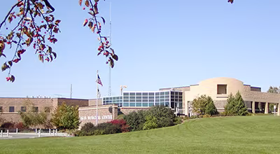 The Eagan Municipal Center building viewed from a grassy hill with autumn trees.