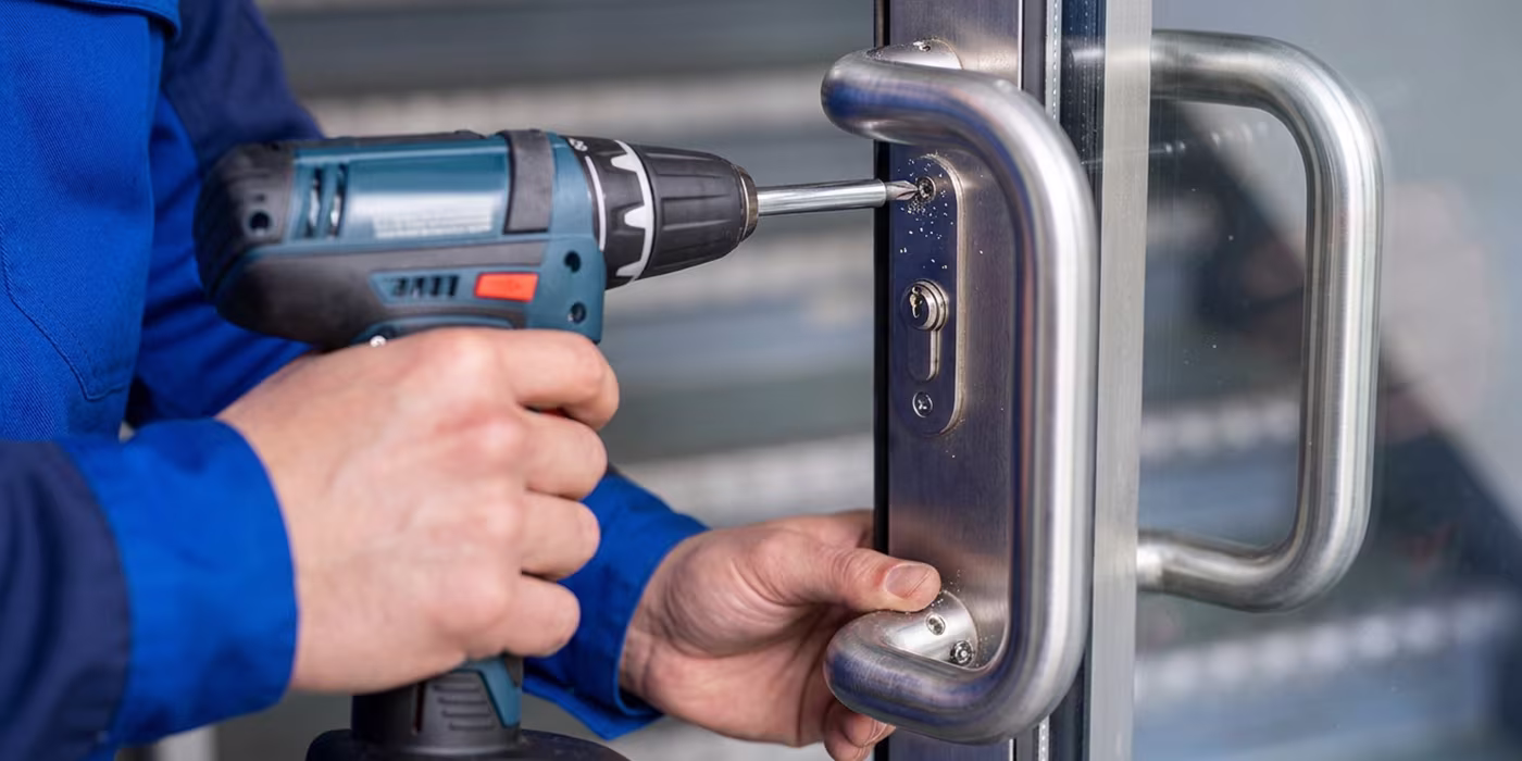 Locksmith repairing a commercial door lock and panic bar in Minneapolis